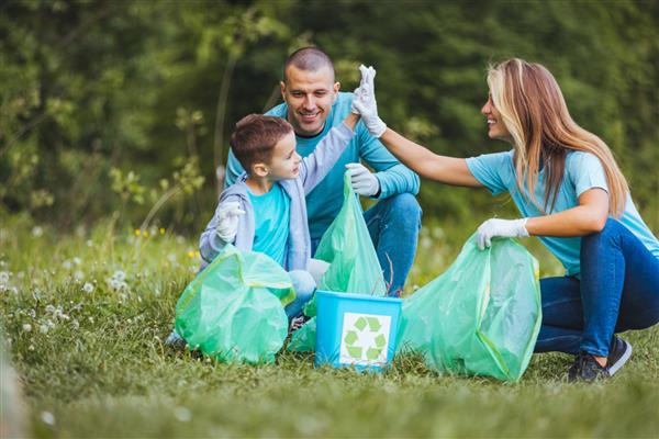 مادر پدر و فرزند برای تمیز کردن جنگل زباله جمع می کنند آنها با هم در طبیعت هستند و زباله ها را در کیسه ها جمع آوری می کنند مفهوم اکولوژی و بازیافت