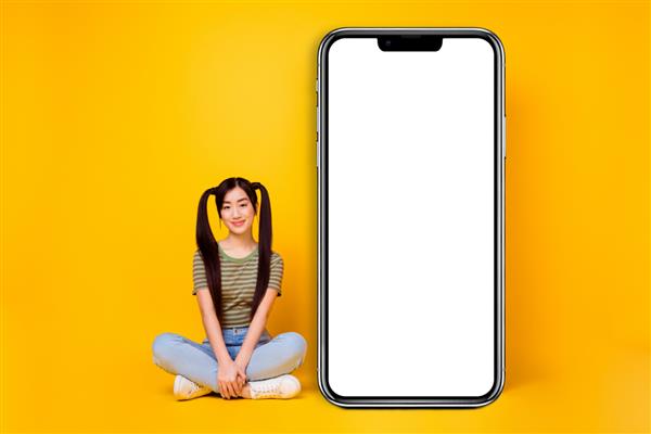 عکس دختر وبلاگ نویس ناز که در کنار صفحه نمایش تلفن بزرگ نشسته است یک پست جدید در سبک زندگی جدا شده در پس زمینه زرد ایجاد کنید