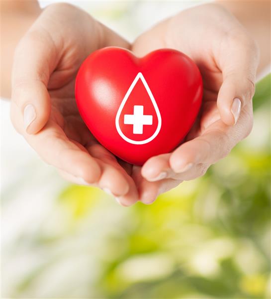 مفهوم مراقبت های بهداشتی دارو و اهدای خون - دست های زن که قلب قرمز را با علامت اهدا کننده روی زمینه طبیعی سبز نگه می دارند