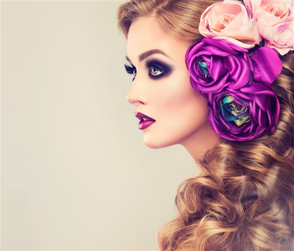 دختر بهاری با آرایش چشم های دودی مد روز مدل موی دم اسبی مجعد با گل های رز مصنوعی بنفش روی سر