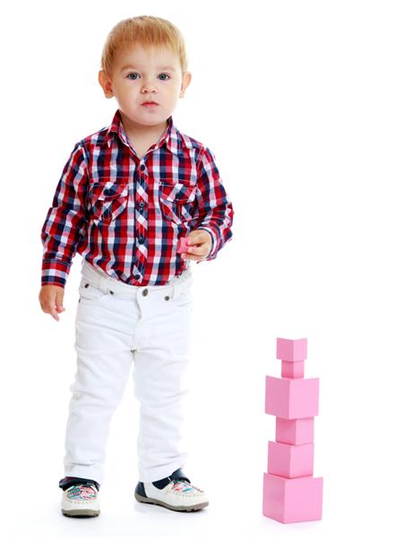 پسر کوچک ناز یک هرم از مکعب ها را قرار می دهد جدا شده روی پس زمینه سفید مرکز کودکان لوتوس