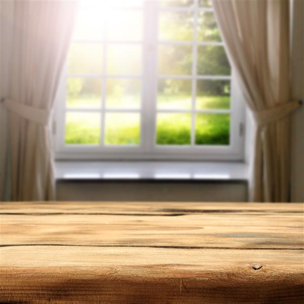 نمای سبز آفتابی باغ در پنجره و فضای میز چوبی