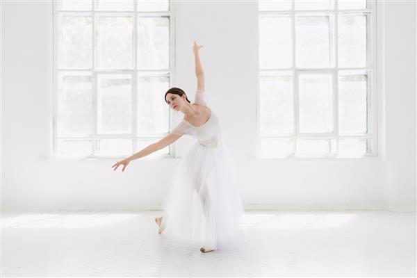 بالرین جوان و فوق العاده زیبا در یک استودیوی سفید رنگ در حال ژست گرفتن و رقصیدن است