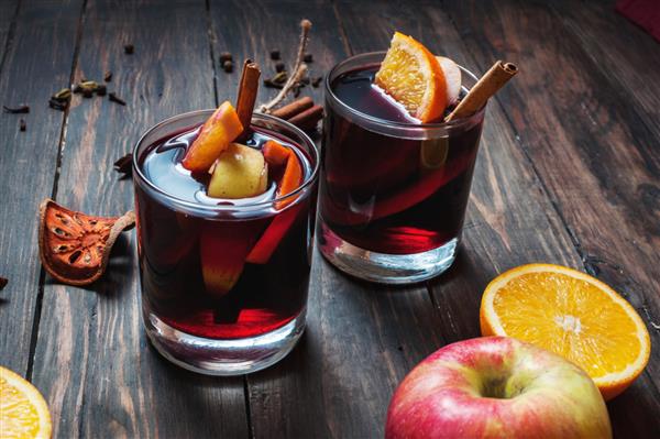 شراب داغ داغ با ادویه جات سیب و پرتقال در زمینه چوب