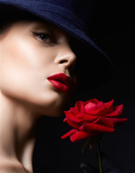 زن جوان زیبا با کلاه و گل دختر دوست داشتنی با آرایش و رز قرمز پرتره زیبایی