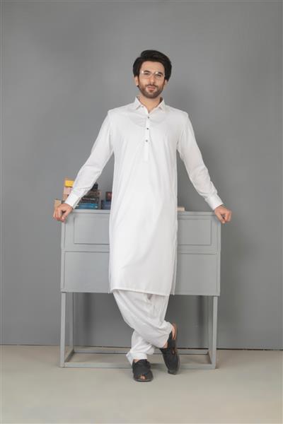 کراچی پاکستان - 14 ماه مه 2022 مرد پاکستانی با لباس سنتی لباس خواب کورتا مدل مد مرد در شروانی ژست گرفتن در استودیو مفهوم مد عروسی