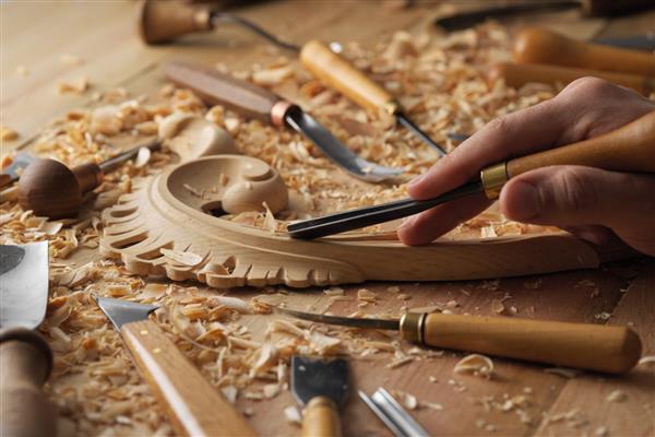 صنعتگر حکاکی با گوگ کارهای چوبی میز کار با تجهیزات ابزار حکاکی روی چوب اسکنه برای کنده کاری