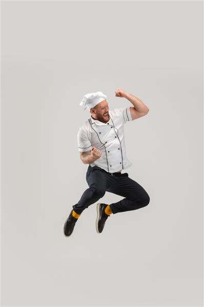 شادی شادی یک مرد ریشدار قفقازی سرآشپز با لباس فرم که روی پس‌زمینه سفید جدا شده است آشپزی شغل حرفه ای مفهوم احساسات خنده دار میم فضای کپی برای تبلیغات
