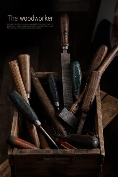 زاویه بالا انواع ابزار نجاری در ظرف چوبی روی نیمکت کارگاه نجاری قرار داده شده است