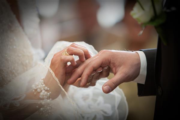 عروس و داماد ناشناخته در حال تبادل حلقه های ازدواج در کلیسا در مراسم عروسی مسیحی