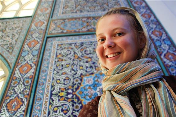 دختر جوان جهانگرد در پس زمینه مسجد جامع اصفهان میراث بزرگ معماری ایرانی موزاییک آبی و دکور غنی