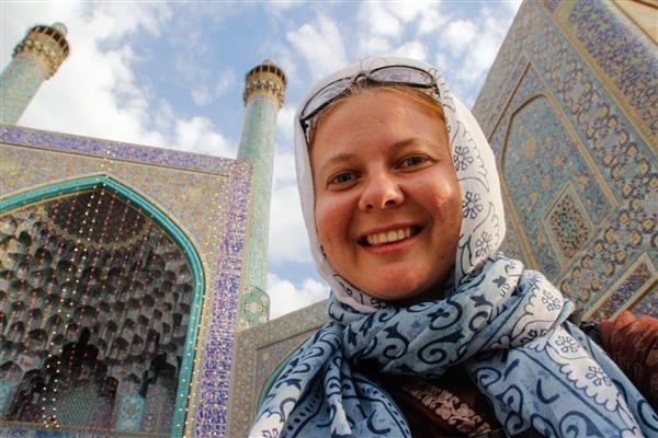 دختر جوان جهانگرد در پس زمینه مسجد جامع اصفهان میراث بزرگ معماری ایرانی موزاییک آبی و دکور غنی