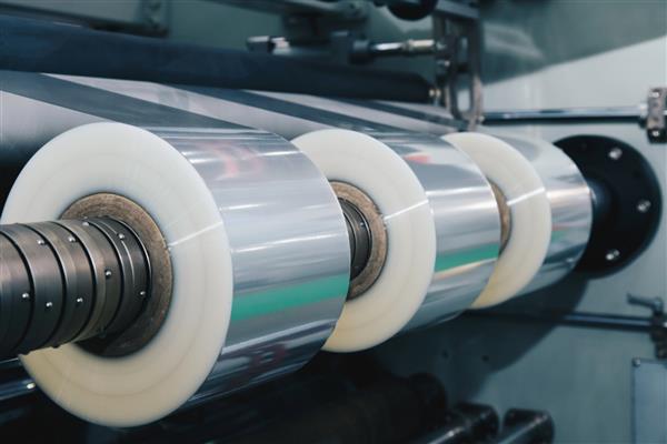 رول فیلم بسته بندی پلاستیکی روی دستگاه بسته بندی اتوماتیک در کارخانه محصولات غذایی مفهوم صنعتی و فناوری سبک عکس و فیلم قدیمی