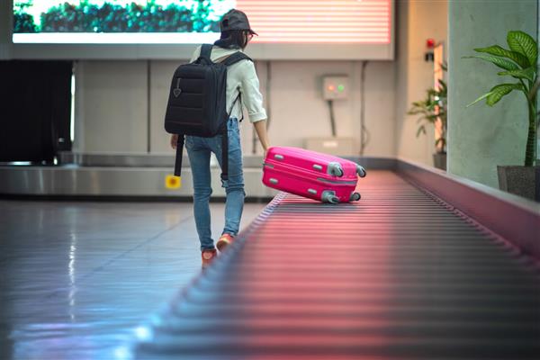 چمدان در تسمه ترمینال ترمینال فرودگاه در حال کشیدن یا بکسل شدن با دست مسافر زن برای دور نگه داشتن در سالن ورود فرودگاه سفر به مقصد مفهومی