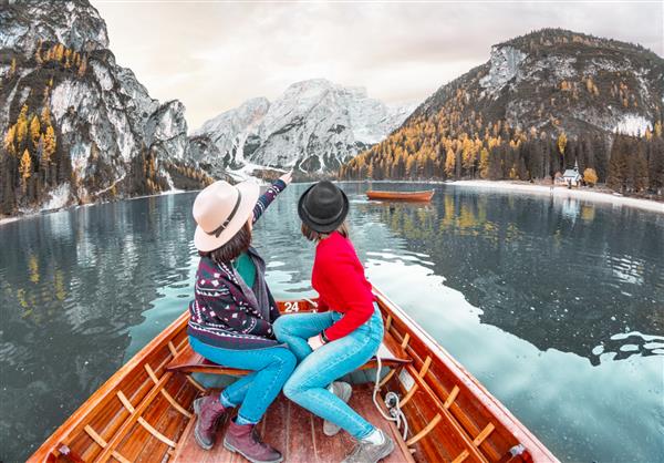 دو دوست زن شاد در تور کروز با قایق یا قایق رانی در دریاچه لاگو دی بریس در آلپ دولومیت ایتالیا