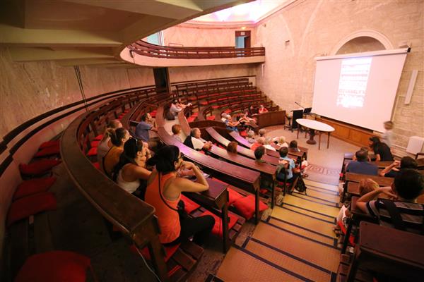 نمای داخلی آمفی تئاتر آناتومی واقع در دانشکده پزشکی باستانی مونپلیه فرانسه 16 سپتامبر 2018 ردیف‌های دایره‌ای از صندلی‌های چوبی با افرادی که به عکس‌ها نگاه می‌کنند