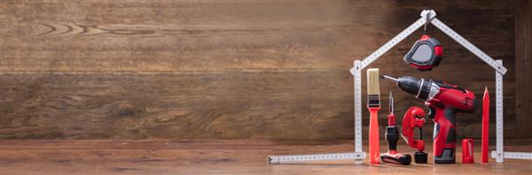 ابزار کار مختلف زیر خانه ساخته شده با نوار اندازه گیری سفید روی میز چوبی