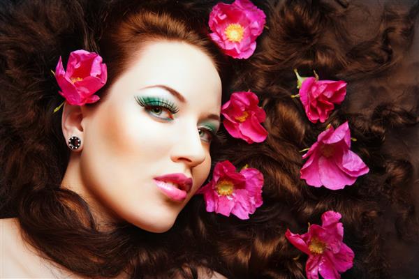 دختر جوان و زیبای سر قرمز با گلهای صورتی در موهایش گل صورتی