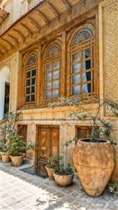 منظره عمودی عمارت قدیمی با پنجره‌های چوبی و گلدان‌های سفالی سنتی مناسب پوستر دیواری ویلا و کافه