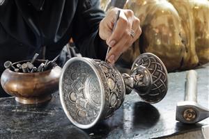 نمای نزدیک از هنر قلم‌زنی روی جام فلزی توسط هنرمند ایرانی ویژه چاپ روی دفترچه، لیوان و پوسترهای صنایع دستی