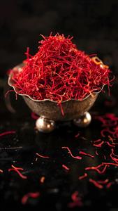 عکس باکیفیت زعفران اصل در ظرف سنتی روی میز مشکی برای طراحی جلد کتاب آشپزی، پوستر دیواری رستوران ایرانی و هتل‌های سنتی