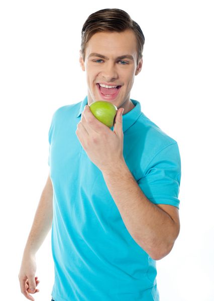 جوان قفقازی در حال گاز گرفتن سیب در زمینه سفید