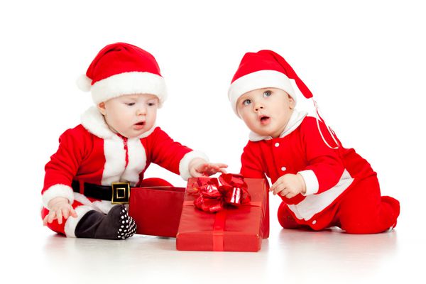 دو بچه کوچک بامزه در لباس بابا نوئل با جعبه هدیه