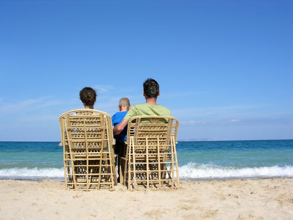 پشت خانواده روی صندلی های راحتی در ساحل