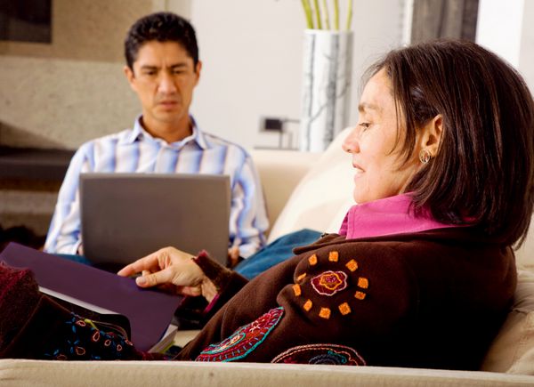 زوج سبک زندگی در خانه که او در حال مطالعه است در حالی که او روی رایانه لپ تاپ است