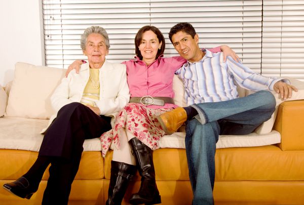 پرتره خانوادگی اسپانیایی که روی مبل خانه در یک محیط داخلی مدرن نشسته است
