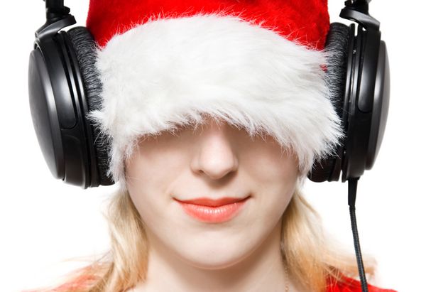 زن جوان با کلاه بابانوئل در حال گوش دادن به موسیقی جدا شده روی سفید
