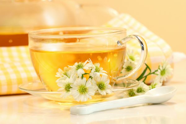 فنجان چای شیشه ای با چای گیاهی و گل