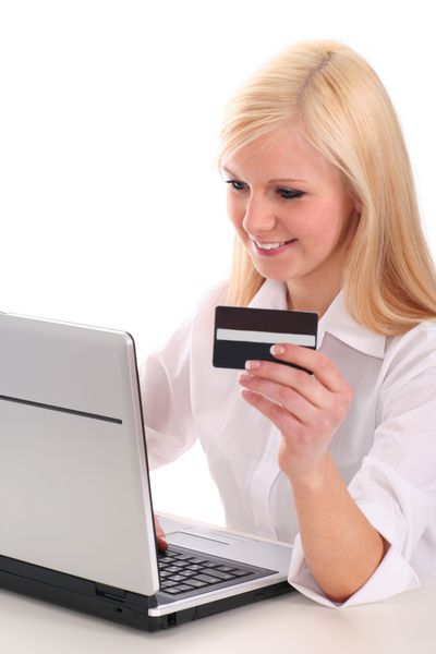 زن با استفاده از لپ‌تاپ کارت اعتباری در دست دارد