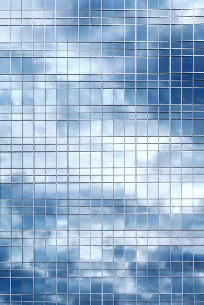 انعکاس یک آسمان ابری در دیوار شیشه ای یک ساختمان اداری
