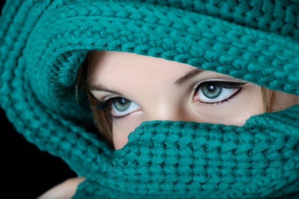 زن جوان با آرایش سرمه سیاه روی چشم ها به مد سنتی خاورمیانه که صورتش را با روسری سبز می پوشاند