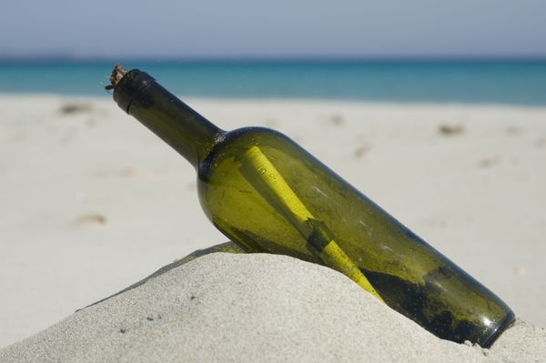 بطری قدیمی با یک پیام در داخل پس زمینه آبی دریا ساحل منظره