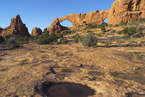 دو طاق و استخر کوچک در یک دیوار سنگی طبیعی عظیم در پارک ملی آرچز در ایالات متحده آمریکا