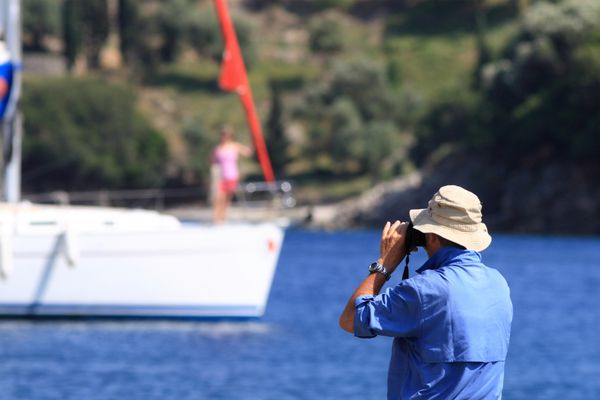 مردی که از یک قایق تفریحی در خلیج عکس می گیرد