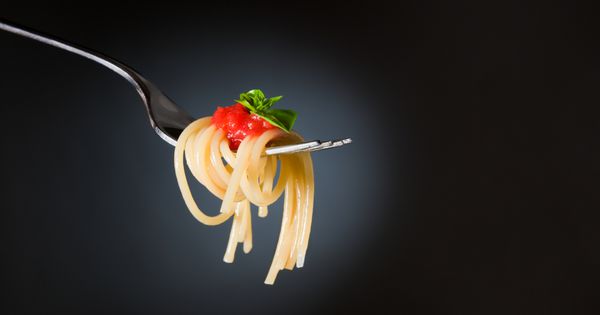 ماکارونی اسپاگتی با گوجه فرنگی و ریحان روی چنگال غذای عالی ایتالیایی فضایی برای متن تصویر استودیو حرفه ای