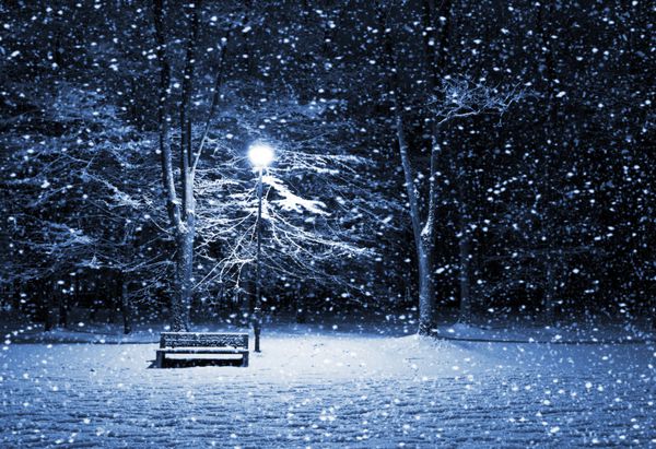 نمای نیمکت و فانوس درخشان در میان برف شلیک شب