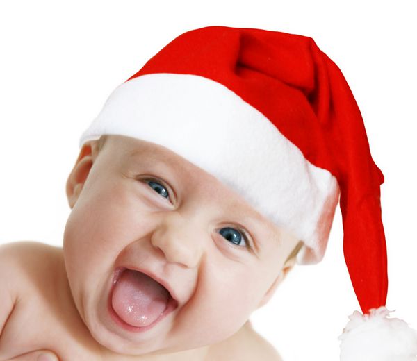 کودک در کلاه کریسمس به دوربین در پس زمینه سفید نگاه می کند