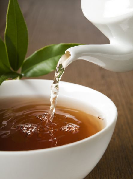 فنجان چای سبز در حال ریختن عکس از نزدیک