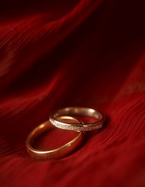 نمای نزدیک از حلقه های ازدواج روی مخمل قرمز DOF بر الماس تمرکز دارد