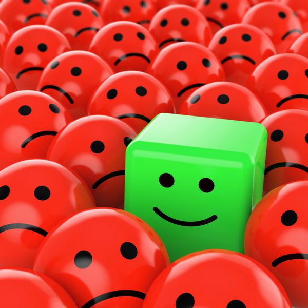 یک شکلک مکعبی شاد سبز بین بسیاری از دیگران کروی قرمز غمگین به عنوان مفهومی برای تفاوت منحصر به فرد خوش بینانه مثبت