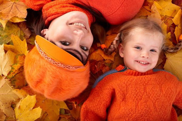 خانواده شاد با فرزند در برگ نارنجی پاییزی فضای باز