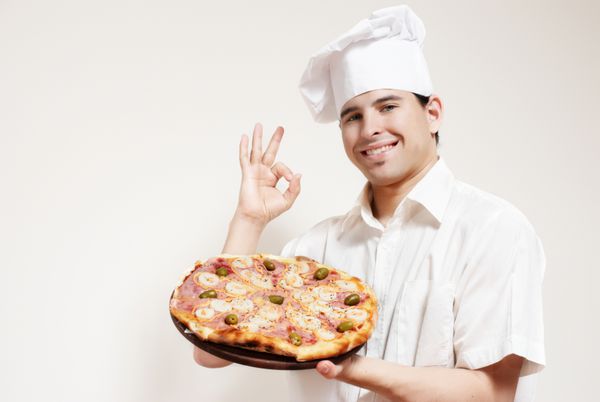 پرتره آشپز جذاب شاد با یک پیتزا در دست