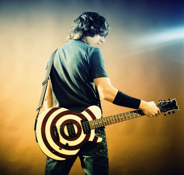تصویری از یک مرد جوان با گیتار در پس‌زمینه سیاه