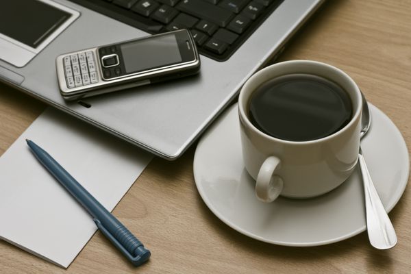 ارتباطات تجاری - لپ تاپ تلفن همراه و فنجان قهوه روی دسکتاپ