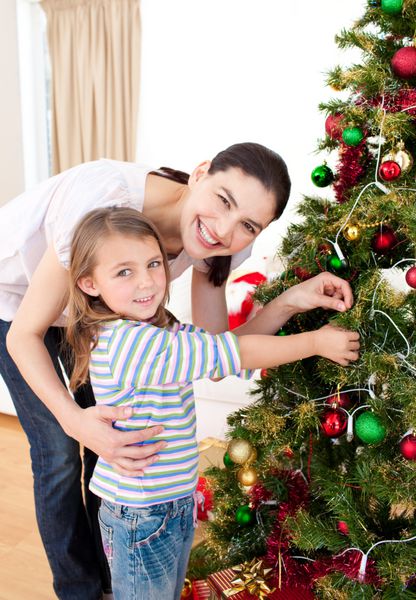 مادر و دخترش در حال تزئین درخت کریسمس در خانه