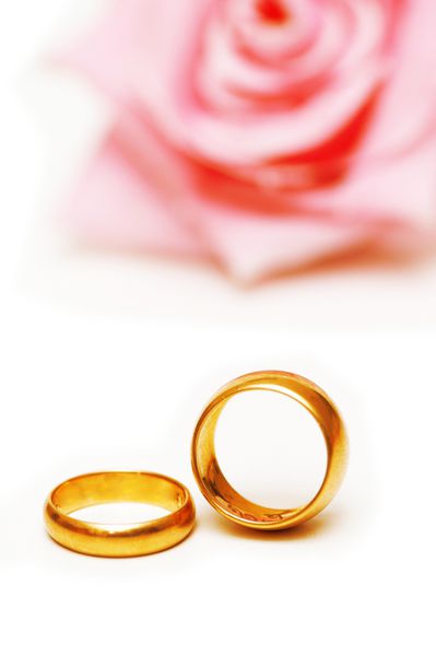 دو حلقه ازدواج طلایی و یک گل رز صورتی